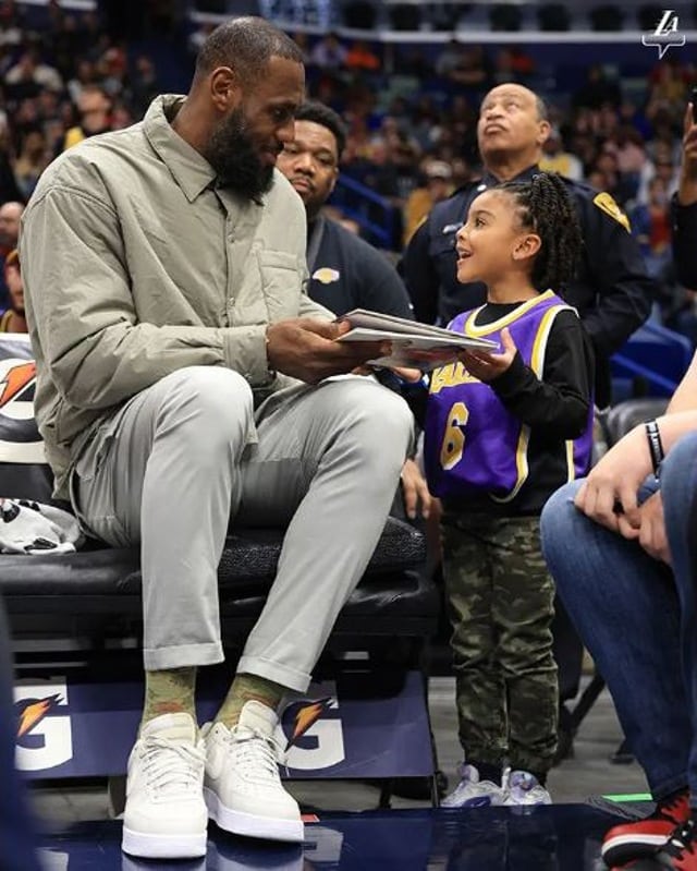 LeBron James signs 'I Promise' book for child during Lakers game