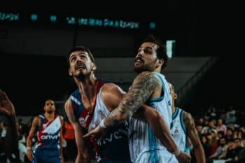 Two basketball players battle for position near the basket during an indoor game