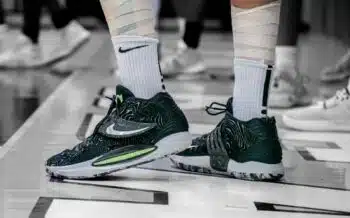 Basketball player in taped socks and high-top sneakers standing on an indoor court