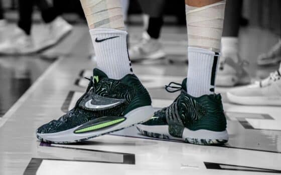 Basketball player in taped socks and high-top sneakers standing on an indoor court